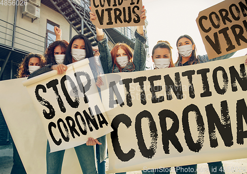 Image of Young people in face masks protesting of stop coronavirus pandemic on the street