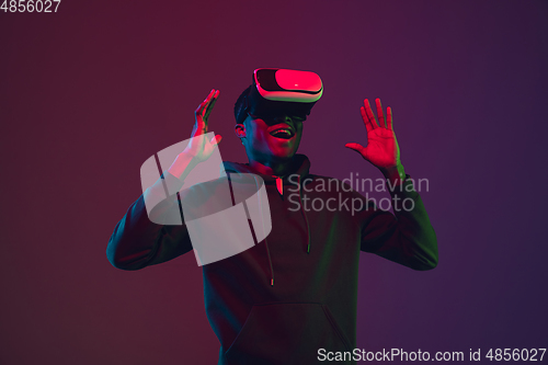 Image of African-american man\'s portrait in VR-headset isolated on gradient studio background in neon light