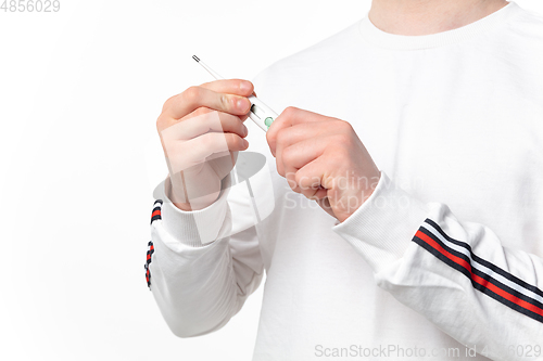 Image of How coronavirus changed our lives. Close up of male hands holding thermometer, taking temperature on white background