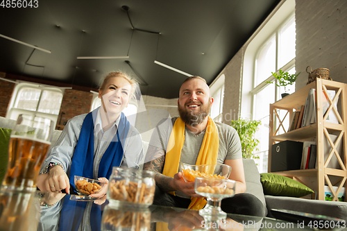 Image of Excited family watching football, sport match at home, beautiful couple