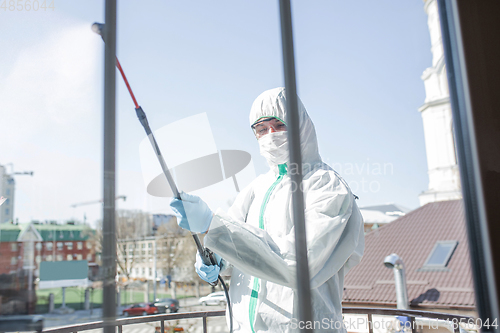 Image of Coronavirus Pandemic. A disinfector in a protective suit and mask sprays disinfectants in the house or office