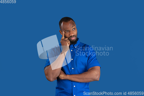 Image of Monochrome portrait of young african-american man on blue studio background