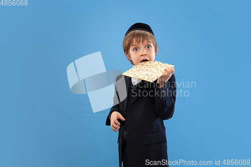 Image of Portrait of a young orthodox jewish boy isolated on blue studio background, meeting the Passover