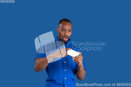 Image of Monochrome portrait of young african-american man on blue studio background