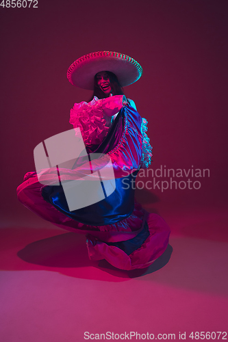 Image of Fabulous Cinco de Mayo female dancer on purple studio background in neon light