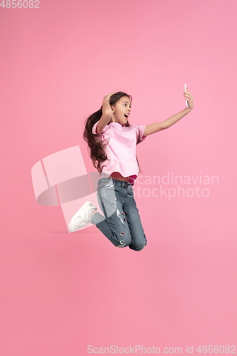 Image of Caucasian little girl portrait isolated on pink studio background, emotions concept