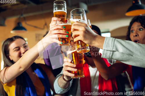 Image of Sport fans cheering at bar, pub and drinking beer while championship, competition is going