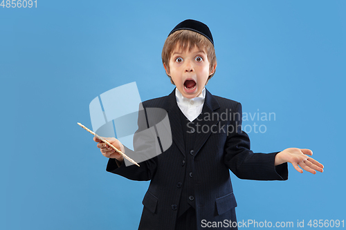 Image of Portrait of a young orthodox jewish boy isolated on blue studio background, meeting the Passover