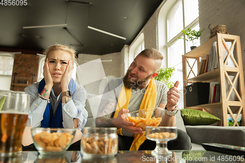 Image of Excited family watching football, sport match at home, beautiful couple