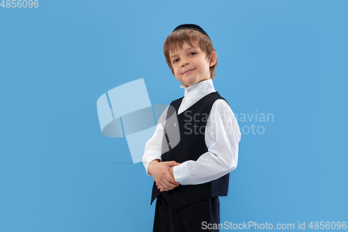 Image of Portrait of a young orthodox jewish boy isolated on blue studio background, meeting the Passover