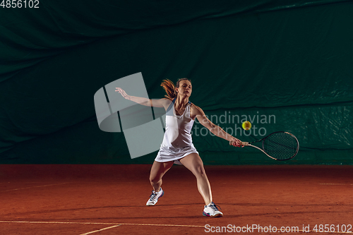 Image of Young caucasian professional sportswoman playing tennis on sport court background