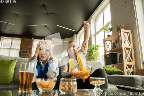 Image of Excited family watching football, sport match at home, beautiful couple