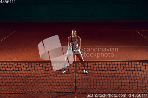 Image of Young caucasian professional sportswoman playing tennis on sport court background