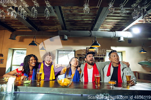 Image of Sport fans cheering at bar, pub and drinking beer while championship, competition is going