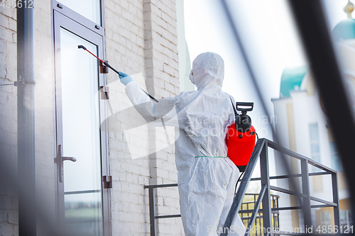 Image of Coronavirus Pandemic. A disinfector in a protective suit and mask sprays disinfectants in the house or office