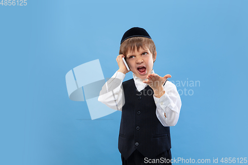 Image of Portrait of a young orthodox jewish boy isolated on blue studio background, meeting the Passover