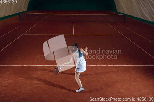 Image of Young caucasian professional sportswoman playing tennis on sport court background