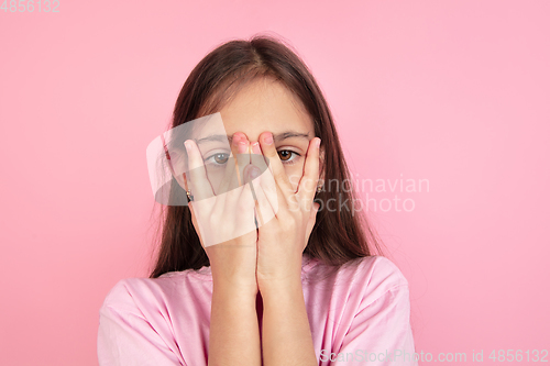 Image of Caucasian little girl portrait isolated on pink studio background, emotions concept