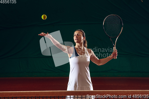 Image of Young caucasian professional sportswoman playing tennis on sport court background