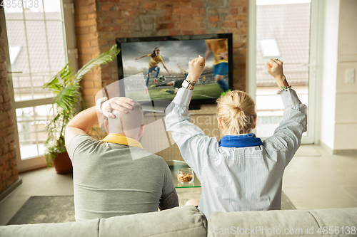 Image of Excited family watching female football, sport match at home, beautiful couple