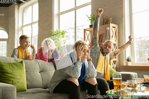 Image of Excited family watching football, sport match at home, top view