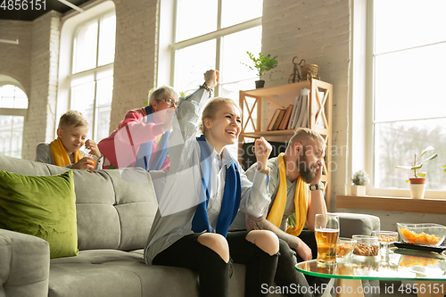 Image of Excited family watching football, sport match at home, top view