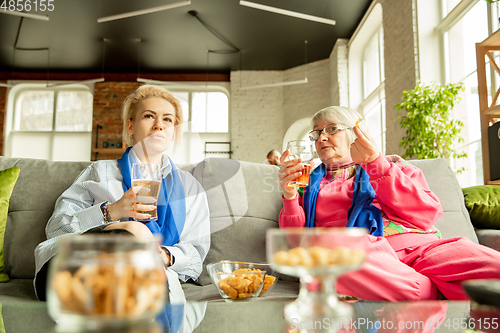 Image of Excited family watching football, sport match at home, grandma and daughter