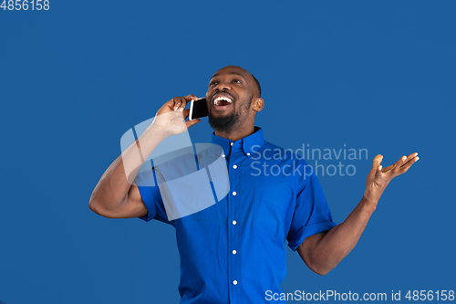 Image of Monochrome portrait of young african-american man on blue studio background