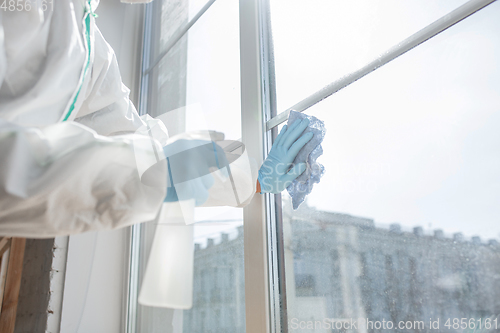 Image of Coronavirus Pandemic. A disinfector in a protective suit and mask sprays disinfectants in the house or office