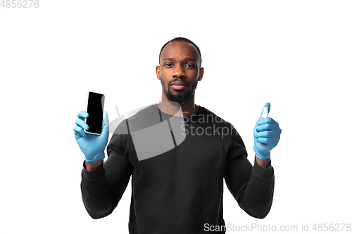 Image of How coronavirus changed our lives. Young man disinfecting gadgets surfaces on white background