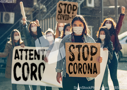 Image of Young people in face masks protesting of stop coronavirus pandemic on the street