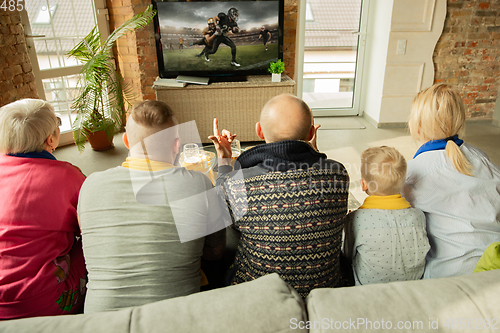 Image of Excited family watching american football, sport match at home