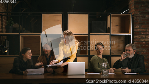 Image of Young colleagues working together in a office styled like classical artworks. Look busy, attented, cheerful, successful. Concept of business, office, finance.