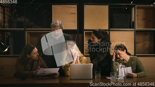 Image of Young colleagues working together in a office styled like classical artworks. Look busy, attented, cheerful, successful. Concept of business, office, finance.