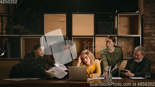 Image of Young colleagues working together in a office styled like classical artworks. Look busy, attented, cheerful, successful. Concept of business, office, finance.