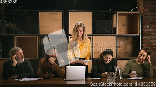 Image of Young colleagues working together in a office styled like classical artworks. Look busy, attented, cheerful, successful. Concept of business, office, finance.