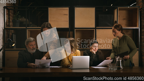 Image of Young colleagues working together in a office styled like classical artworks. Look busy, attented, cheerful, successful. Concept of business, office, finance.