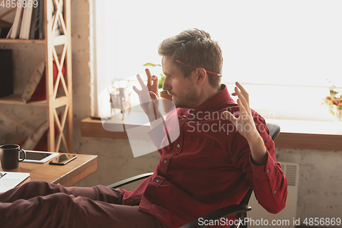 Image of Caucasian entrepreneur, businessman, manager trying to work, looks funny, lazy and spending time