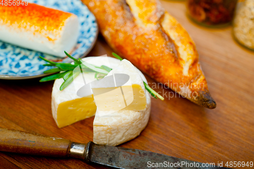 Image of French cheese and fresh  baguette on a wood cutter