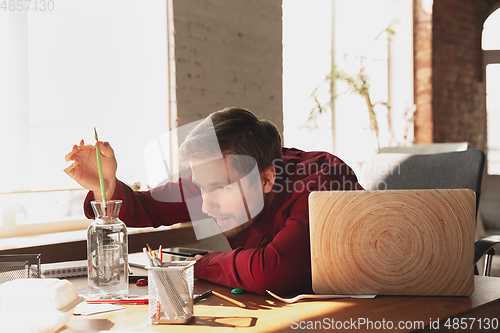 Image of Caucasian entrepreneur, businessman, manager trying to work, looks funny, lazy and spending time