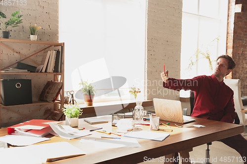 Image of Caucasian entrepreneur, businessman, manager trying to work, looks funny, lazy and spending time