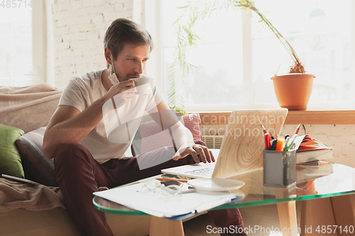 Image of Young man studying at home during online courses for financist, economist, managers