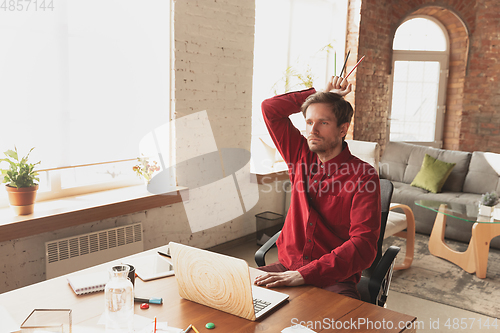 Image of Caucasian entrepreneur, businessman, manager trying to work, looks funny, lazy and spending time