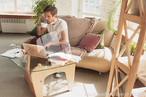 Image of Young man studying at home during online courses for financist, economist, managers