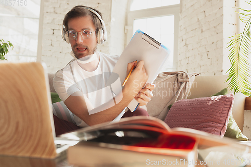 Image of Young man studying at home during online courses for laborer, journalist, developer.