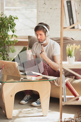 Image of Young man studying at home during online courses for programmer, bug-tester, consulter