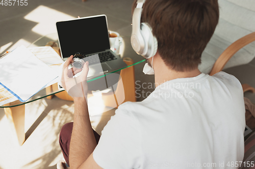 Image of Young man studying at home during online courses for photographer, studio assistant