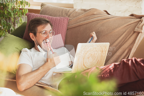 Image of Young man studying at home during online courses for journalist, critics, writers