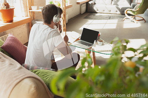 Image of Young man studying at home during online courses for retailer, buyer, teacher