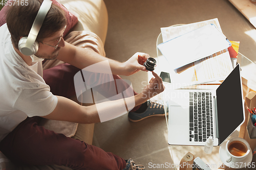 Image of Young man studying at home during online courses for photographer, studio assistant